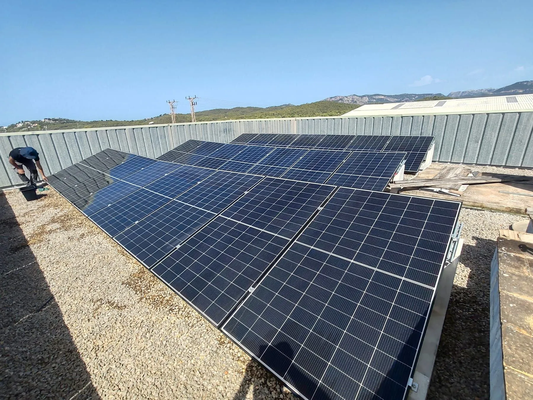 Modulreihen mit Aufständerung auf einem Kiesdach, im Hintergrund die Serra de Tramuntana